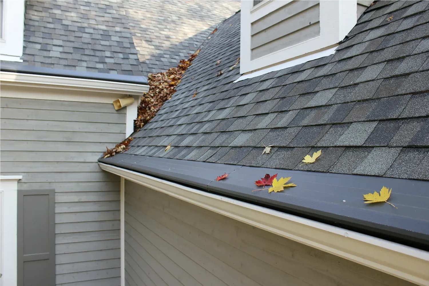 A gray house with gray roof and black Gutter Helmet gutter covers.