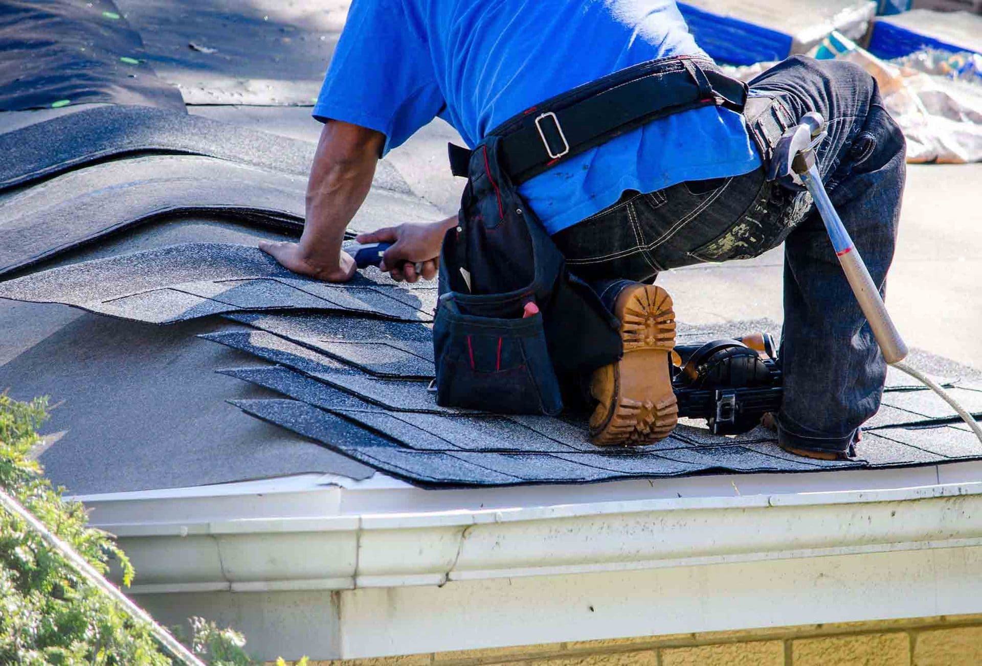 A worker installs new roofing shingles.