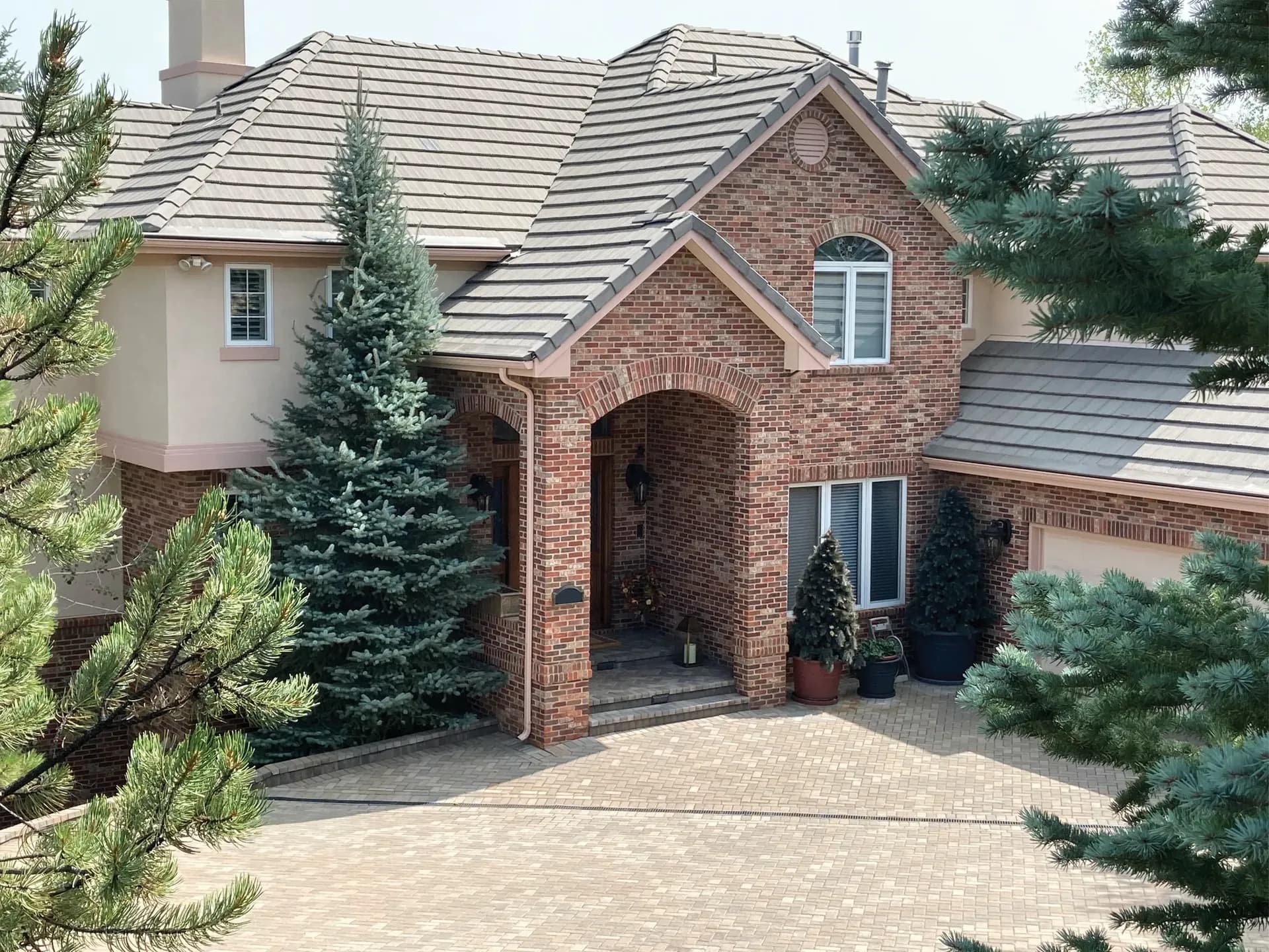 A red brick house with new light gray roofing.